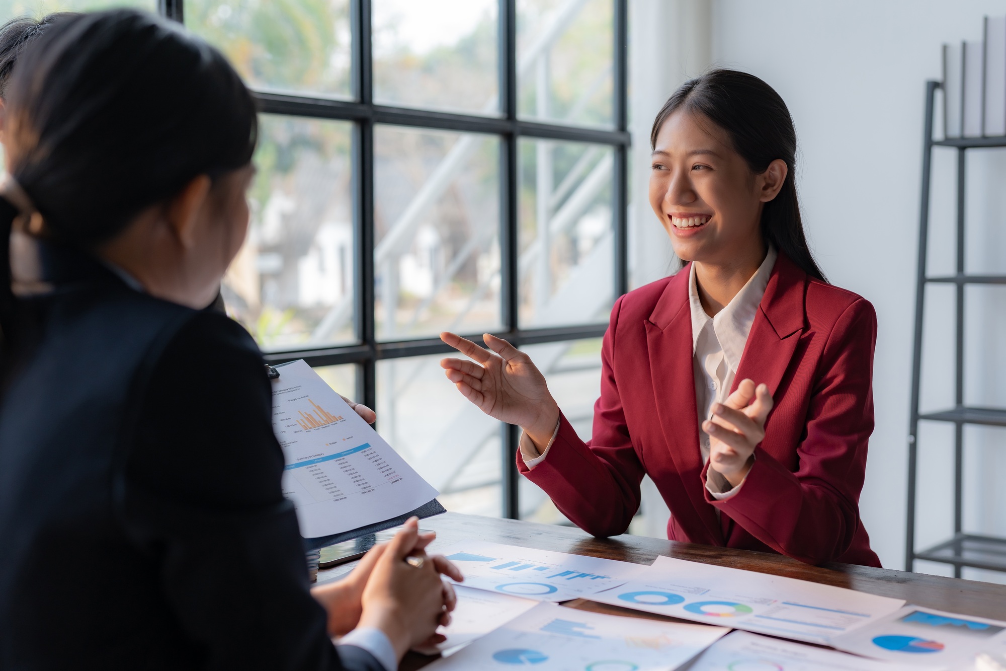 Asian Businesswoman discussing financial report with colleague.